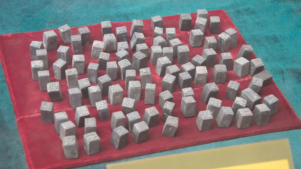 Rows of bronze Chinese movable-type printing blocks on red felt