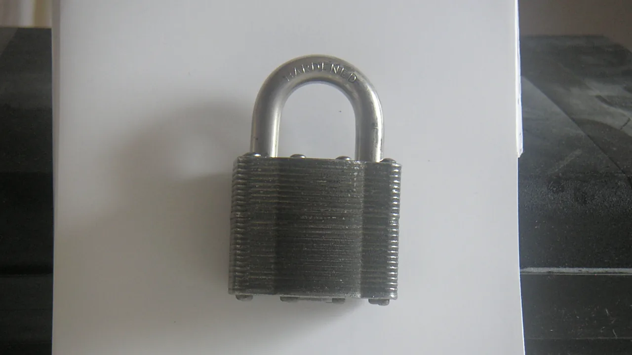 A laminated steel padlock, closed, on a white surface