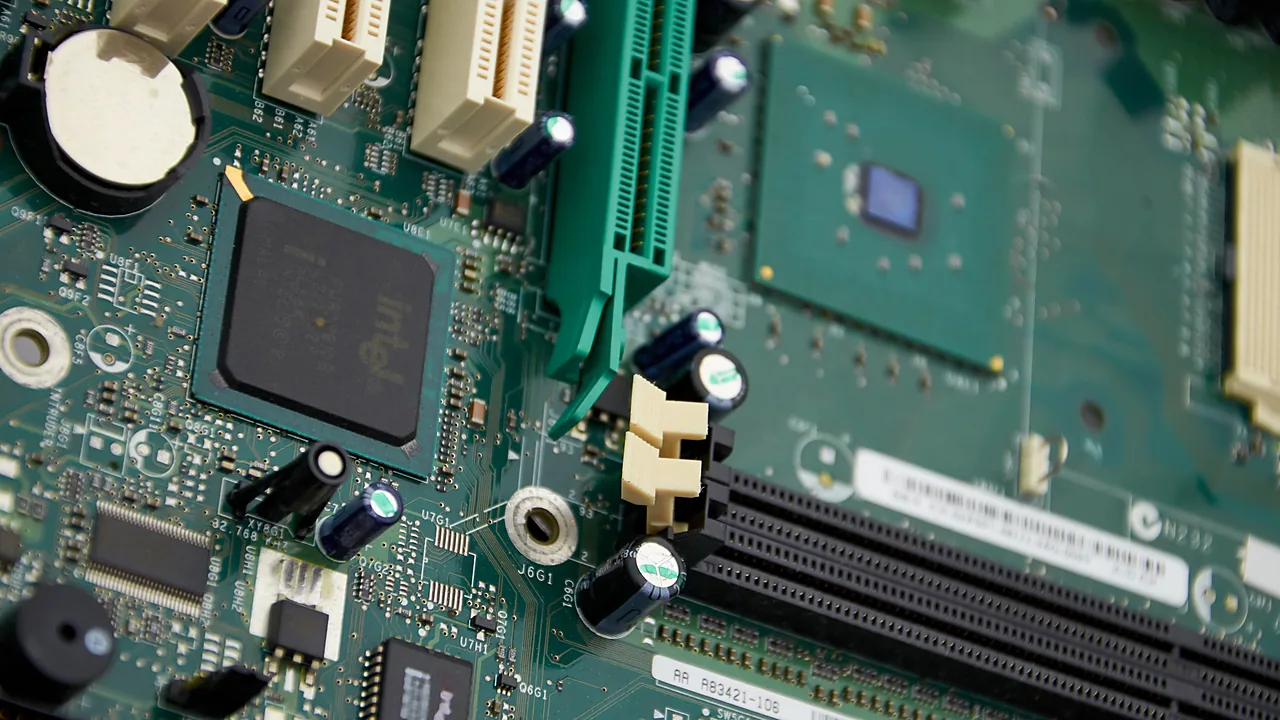Close-up of a computer motherboard showing an Intel chip, PCI slots, and capacitors