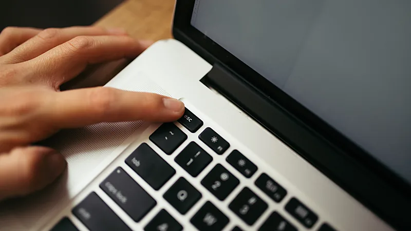 A finger pressing a key on a laptop keyboard