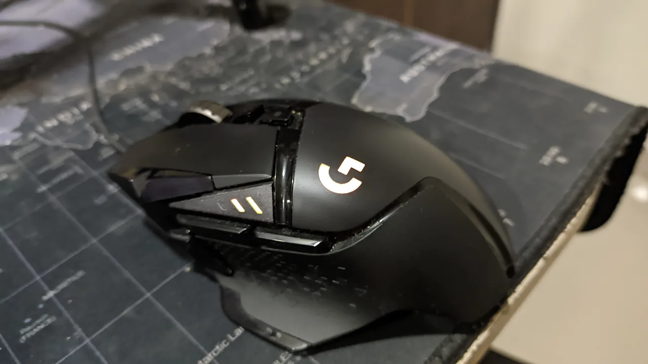 Logitech G502 gaming mouse with glowing G logo on a world-map mouse pad