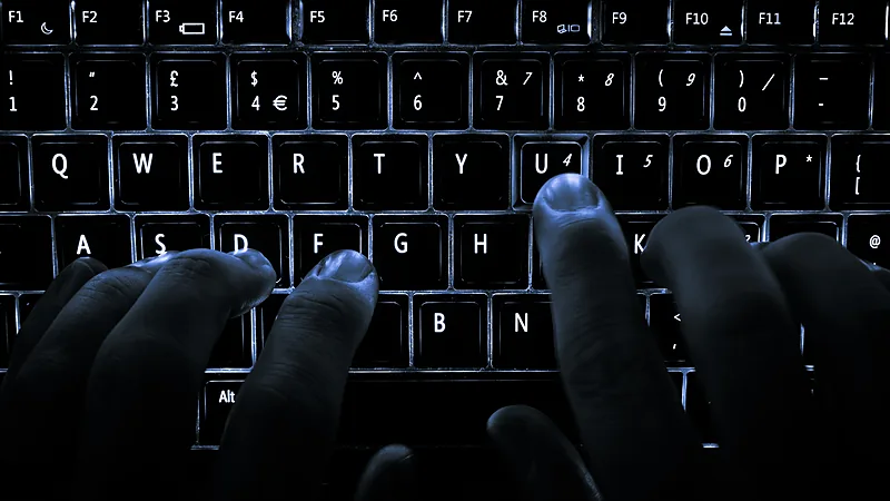 Backlit computer keyboard in the dark with hands typing
