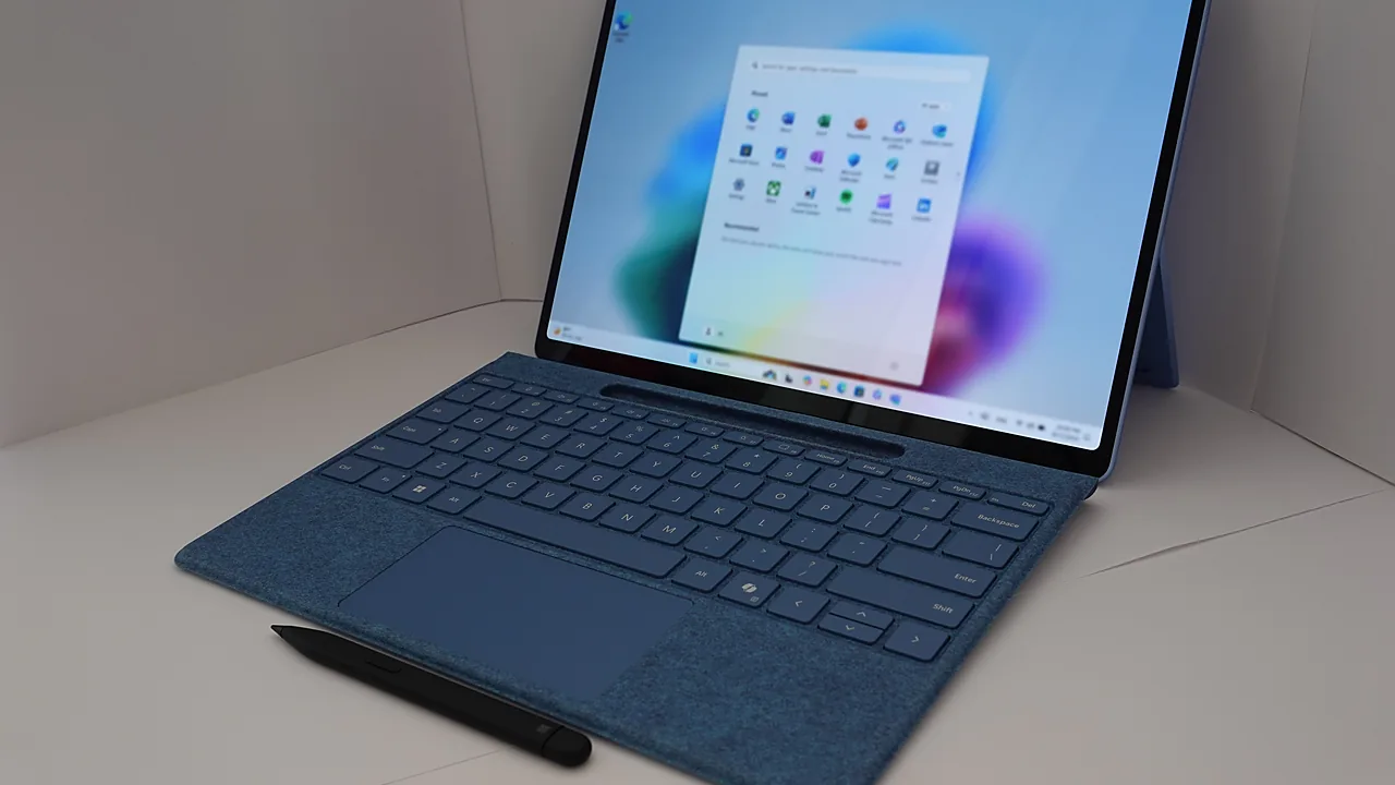 Blue Surface tablet with keyboard and pen showing the Windows 11 Start menu