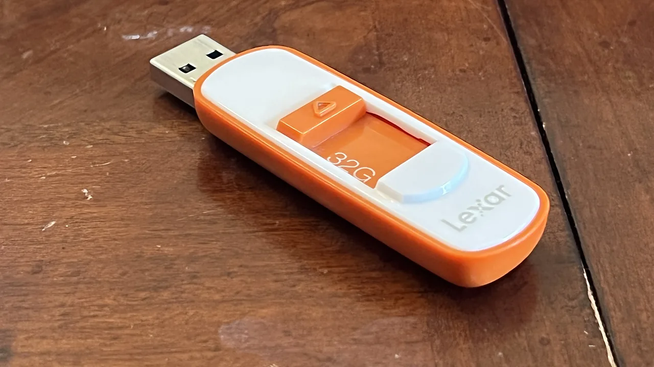 Orange and white Lexar 32 GB USB flash drive on a wooden table