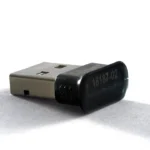 A small black USB Bluetooth dongle lying on a white surface