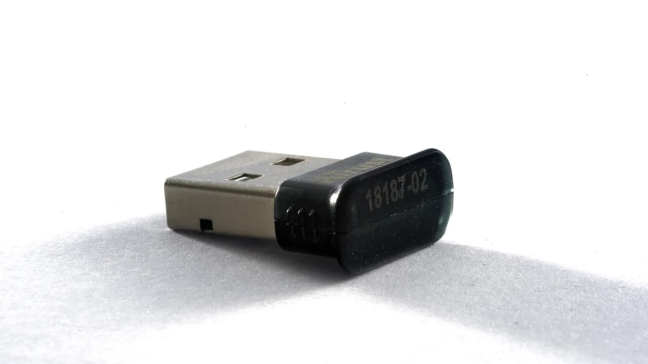 A small black USB Bluetooth dongle lying on a white surface