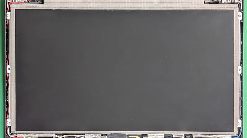 A laptop LCD panel removed from its lid, showing the bare screen assembly and its cabling