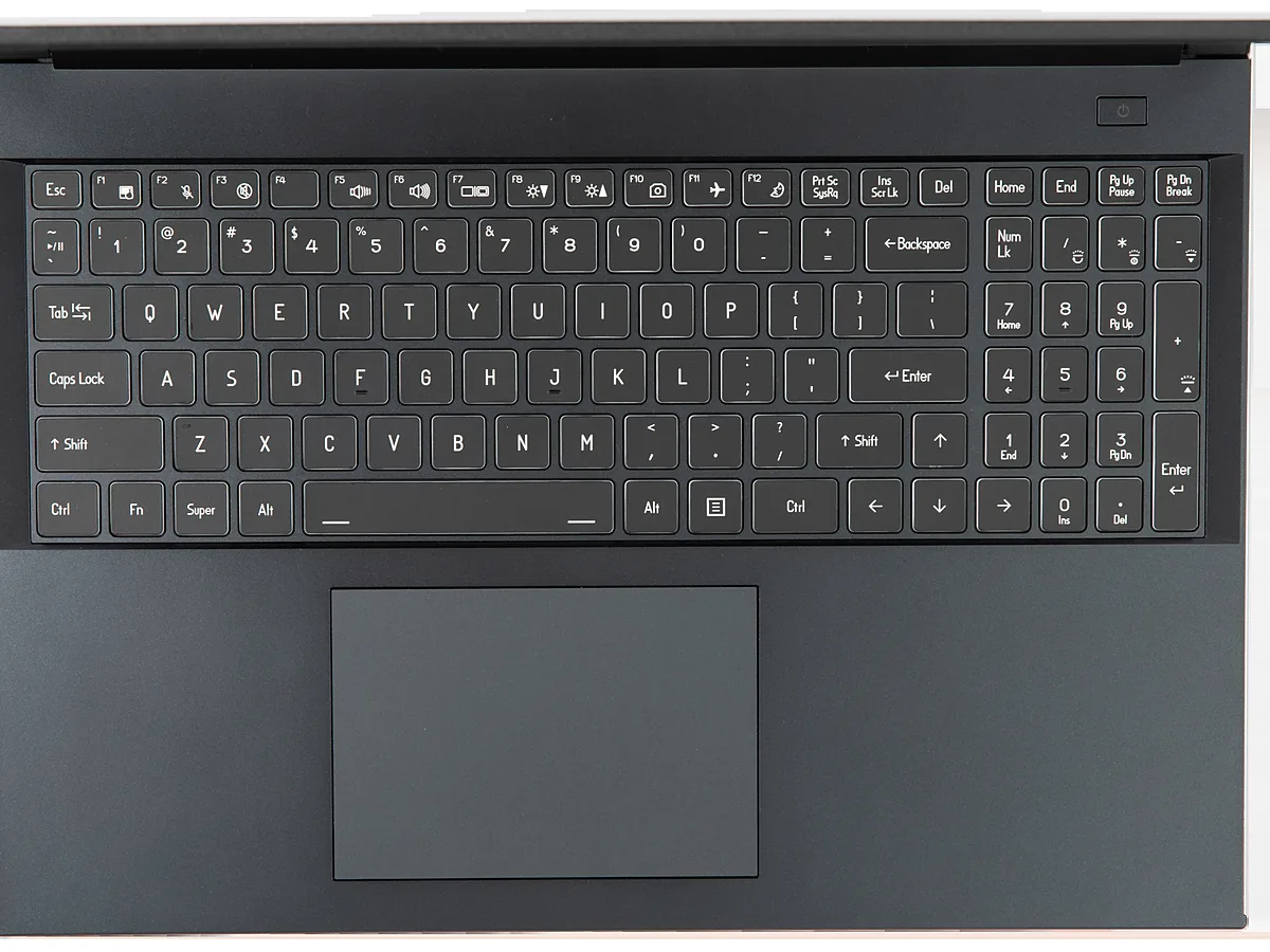 Top-down view of a laptop keyboard and the touchpad below it, with the function row showing symbols for volume, brightness, camera and aeroplane mode.