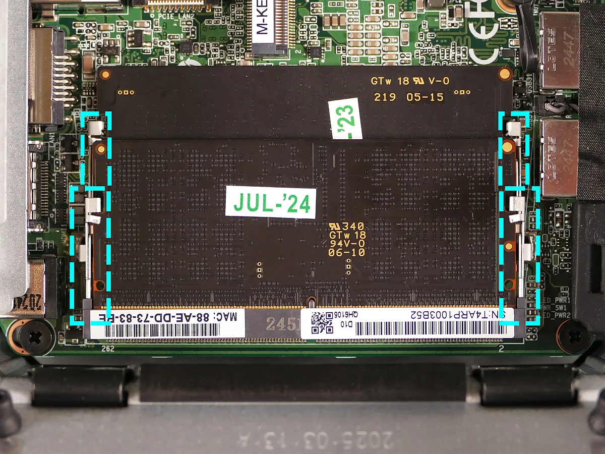 Two memory slots stacked inside a laptop, both holding a module, with the retention clips marked by dashed boxes.