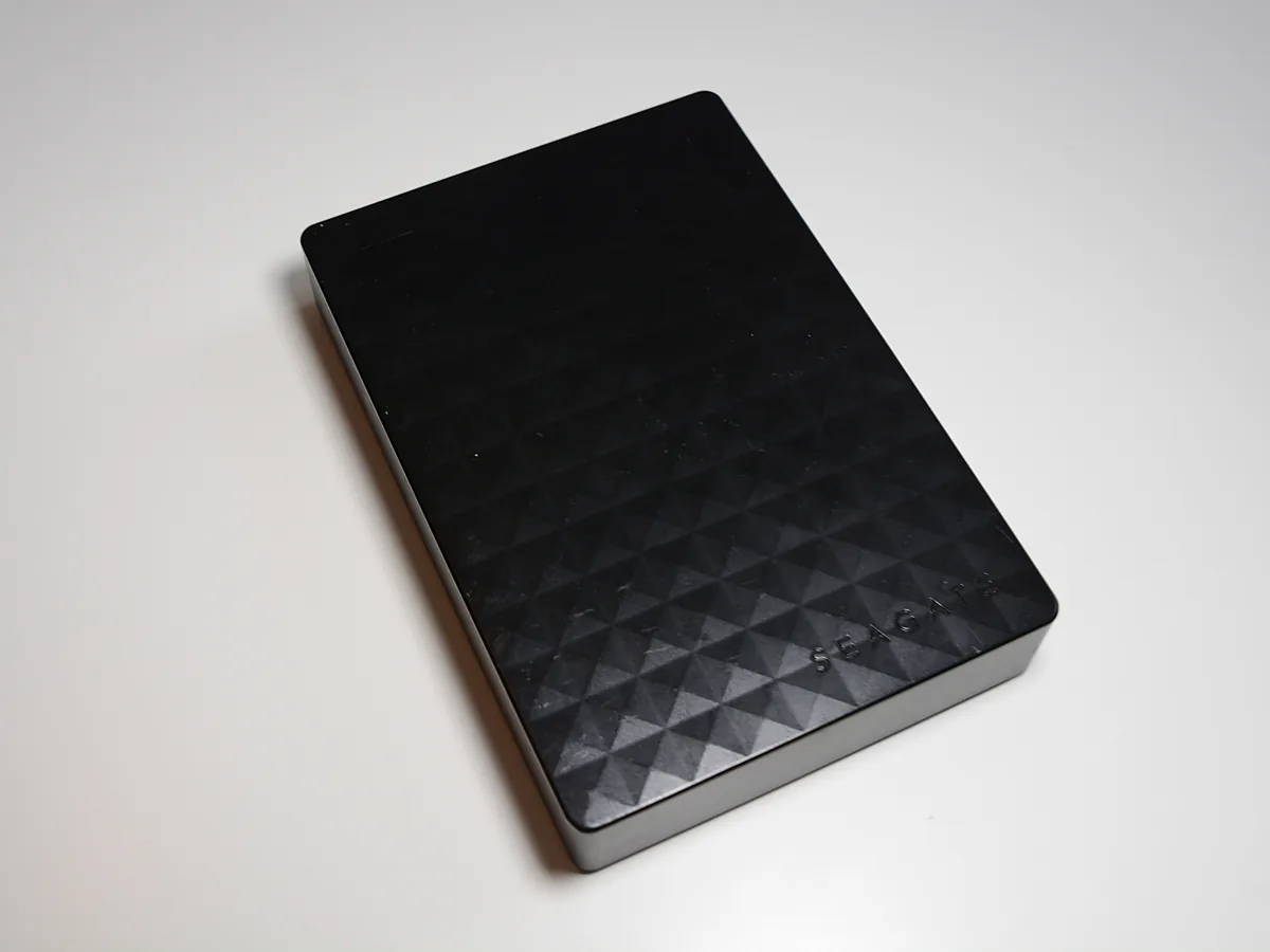 A black Seagate portable external hard drive with a faceted lid, photographed on a white surface.