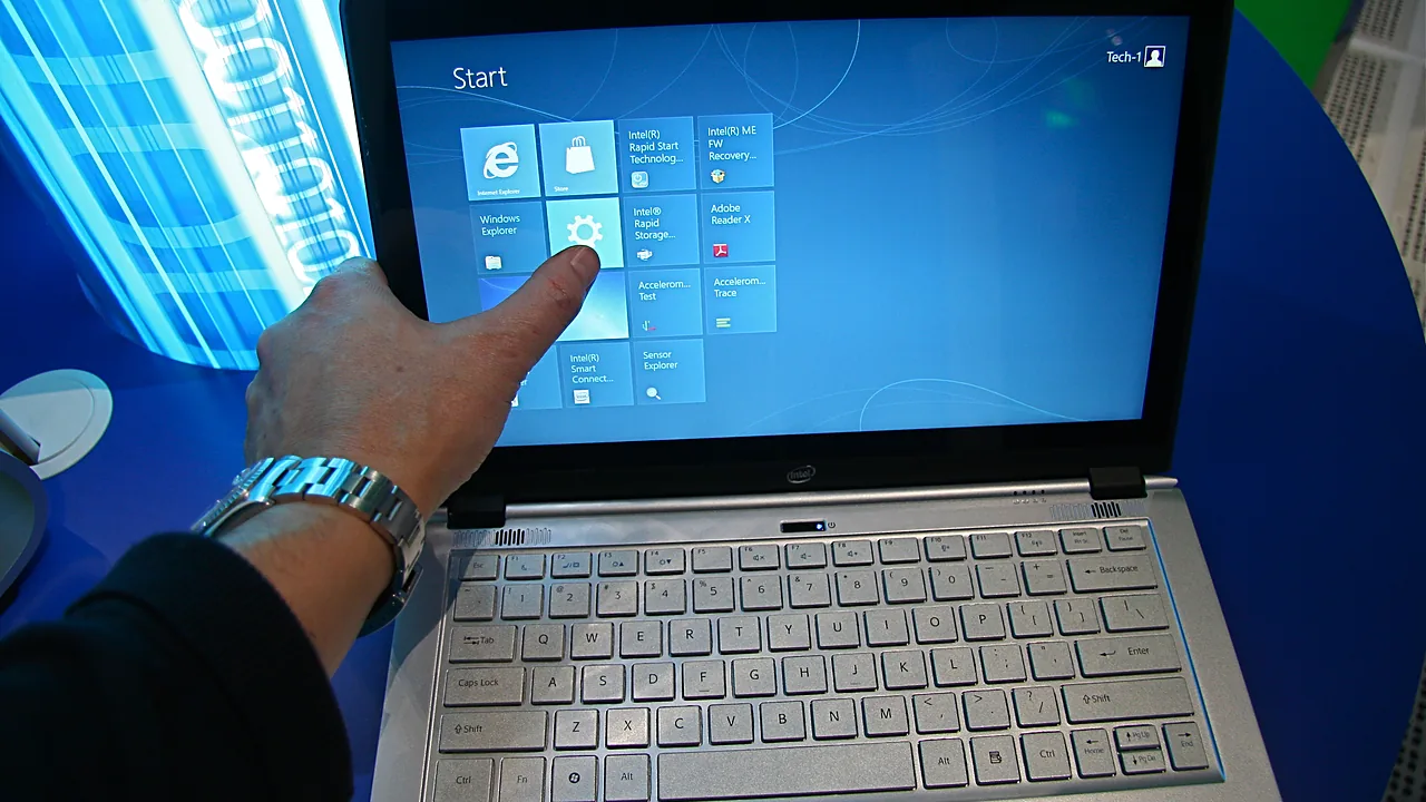 A finger tapping a tile on the touchscreen of a Windows laptop