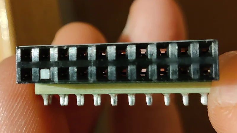 Close-up of the 20-pin connector on a TPM module held between two fingers